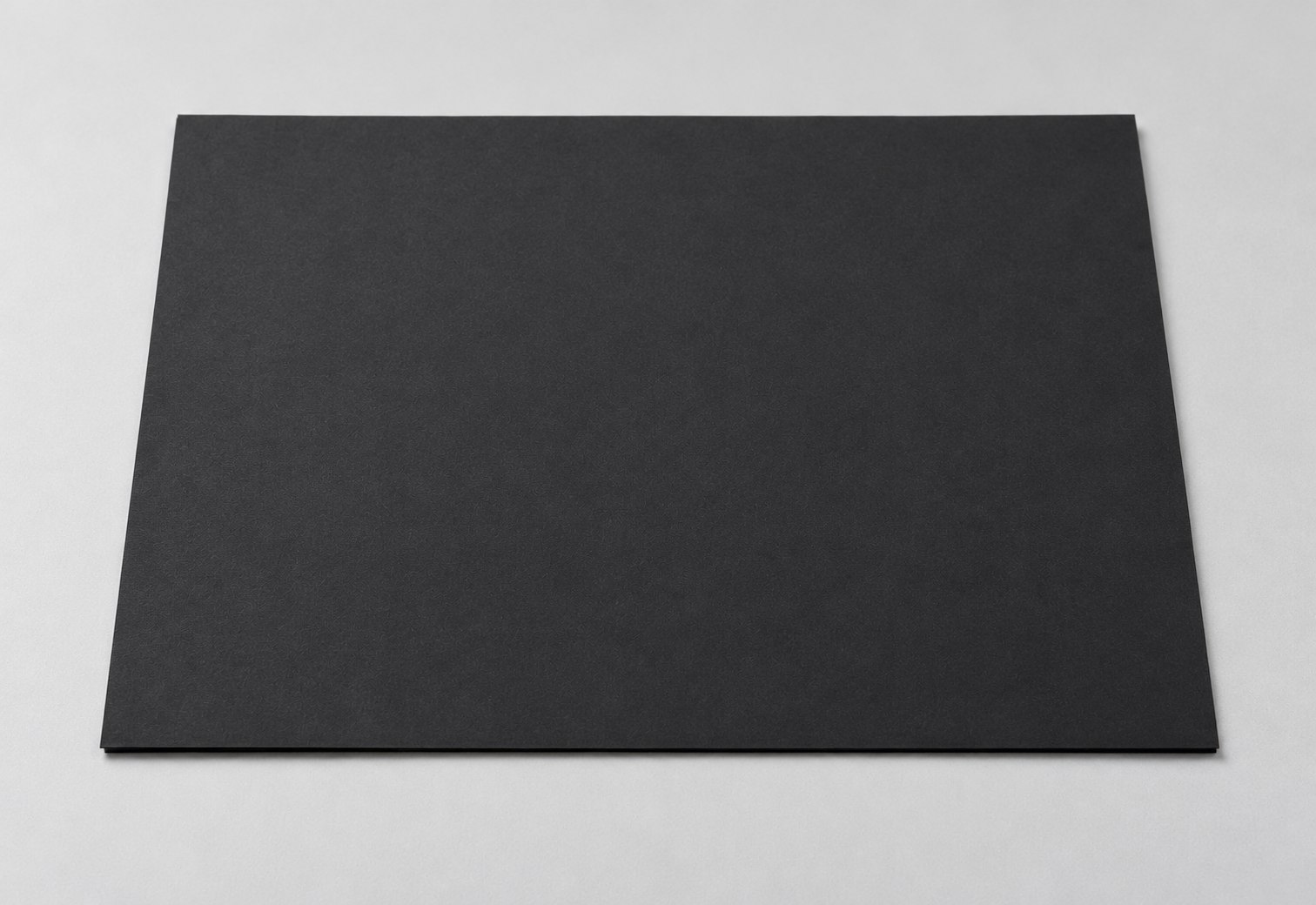 Matte black cardboard sample sheet on a light gray studio surface